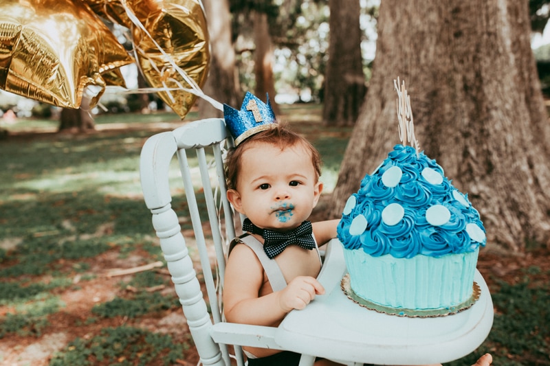 Orlando Cake Smash Photographer, little boy eating cake in highchair looking at camera